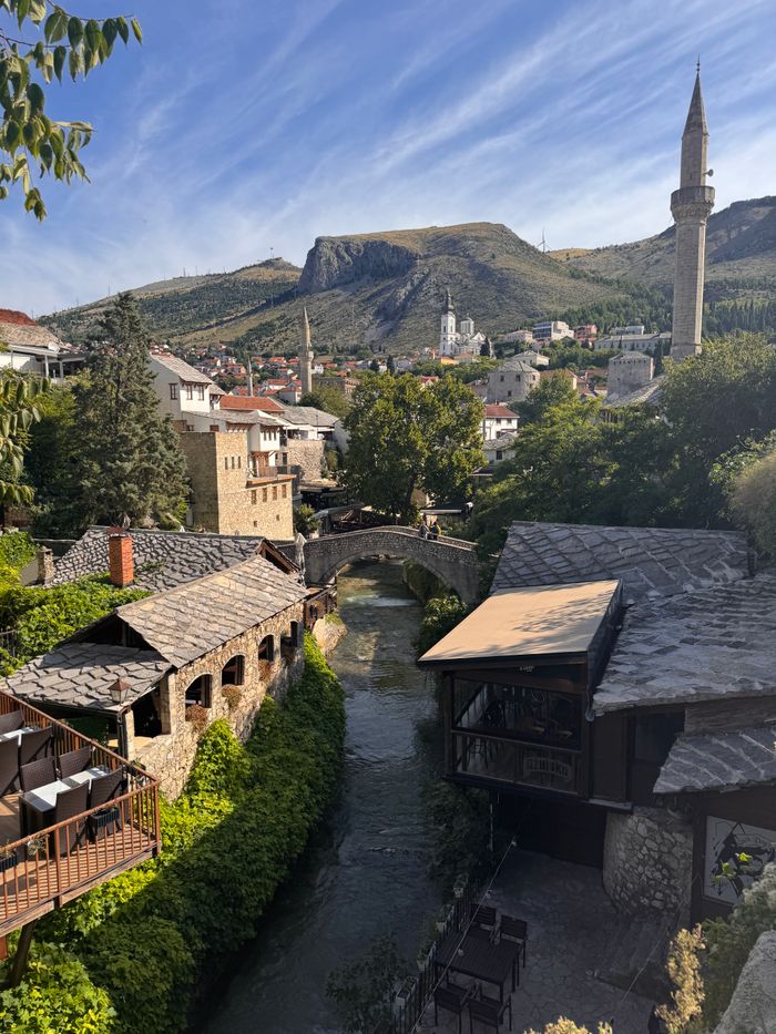 Picturesque cityscape of Mostar featuring a river and Ottoman architecture under a clear sky.