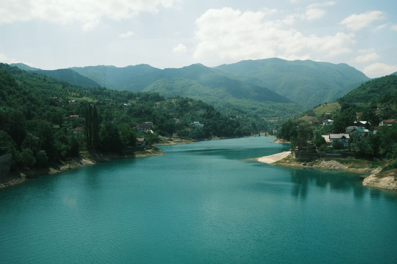 Peaceful river flowing through lush green mountains in Bosnia and Herzegovina.